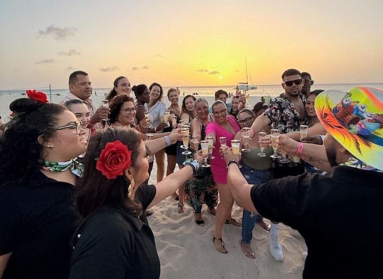 A group of people toasting with champagne on a beach at sunset. 1
