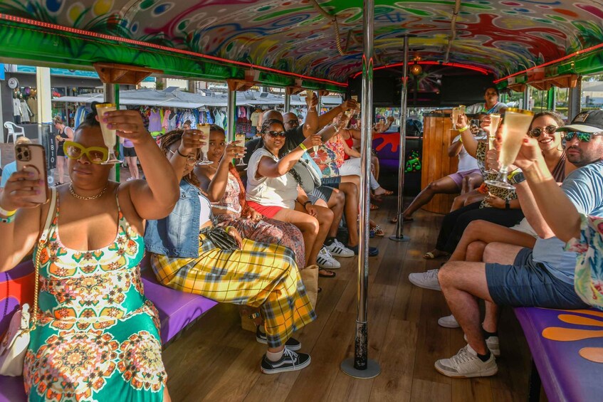 People sitting on a colorful bus, holding drinks. 2