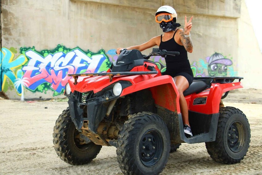 A person on a red ATV with graffiti in the background. 4