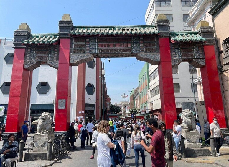 A traditional gate with intricate carvings and lion statues, surrounded by a crowd of people. 3