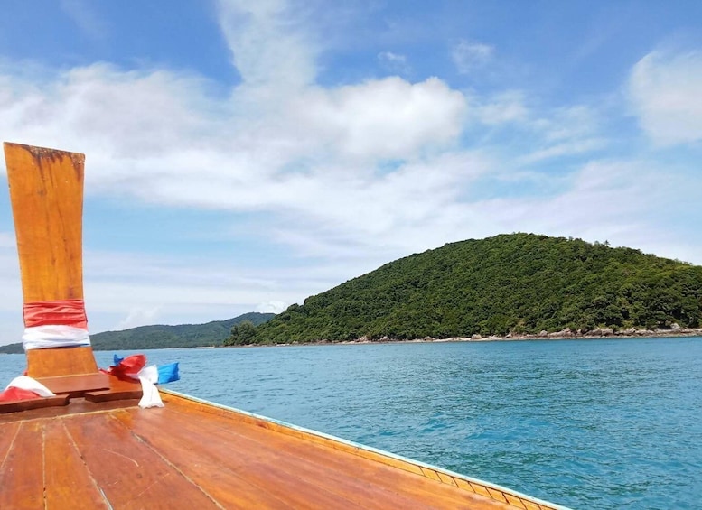 A wooden boat deck with a view of a calm sea and a green hill in the distance. 4