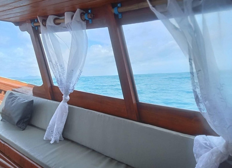 A wooden deck with a cushioned seating area and sheer white curtains. 3
