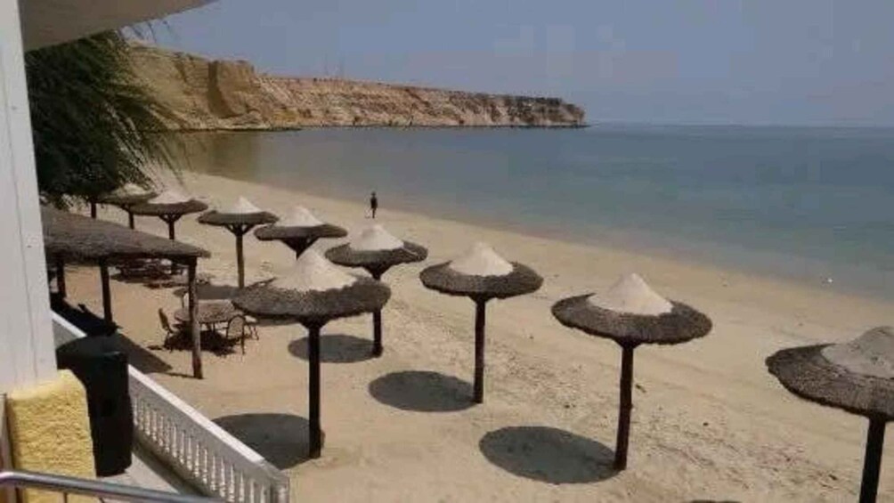 A beach with thatched umbrellas and a staircase leading down to the sand. 5