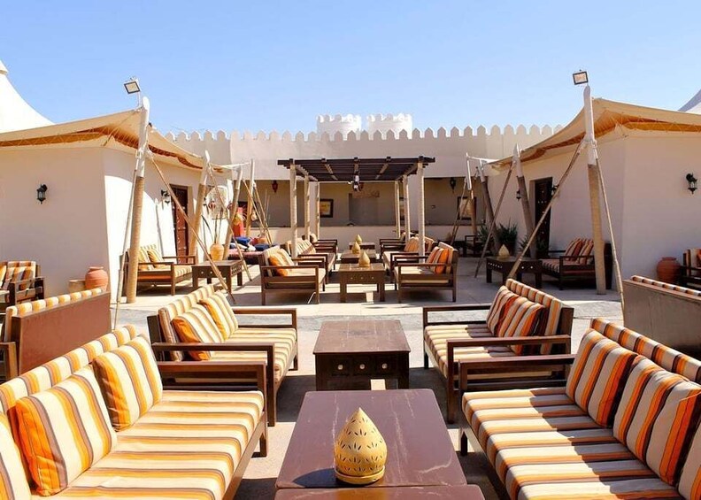 A sunlit outdoor seating area with striped cushions and wooden furniture. 1