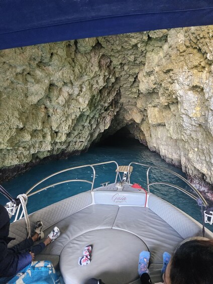 A boat with a 'Gaia' logo, anchored near a rocky cave entrance. 3