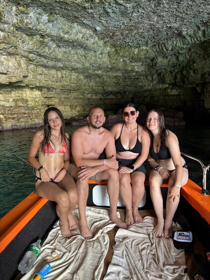 Four people sitting on a boat in a cave with water. 2