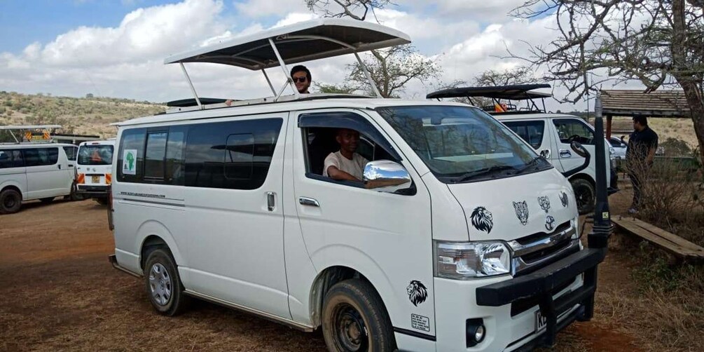A white van with a roof rack and a person standing on top. 2