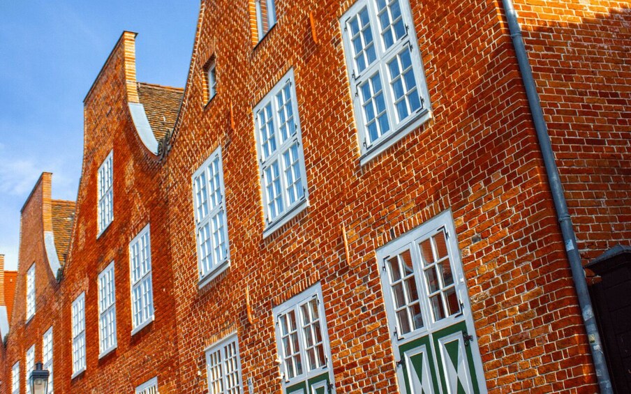A red brick building with white windows and green doors. 2