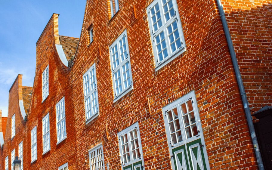 A row of red brick buildings with white window frames and green doors. 2