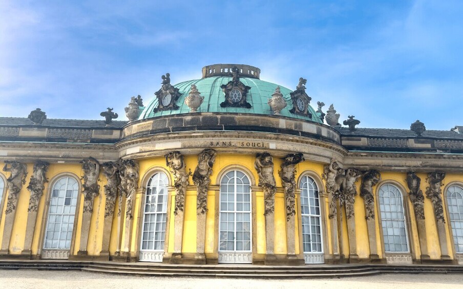 A historic building with a green dome and ornate sculptures. 4