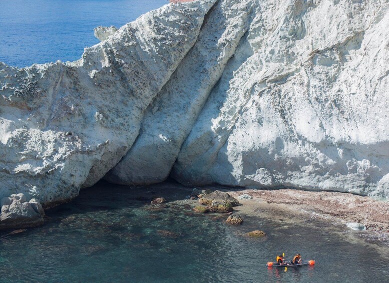 A kayaker navigating a narrow waterway between rocky cliffs. 3