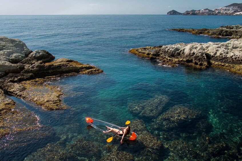 A person kayaking in clear blue waters surrounded by rocky formations. 1