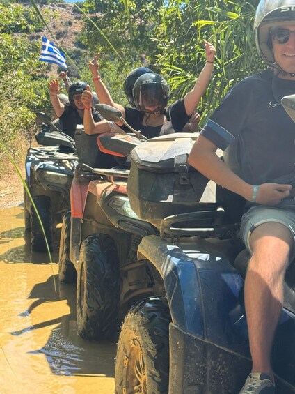 People riding ATVs on a muddy path with a flag. 1