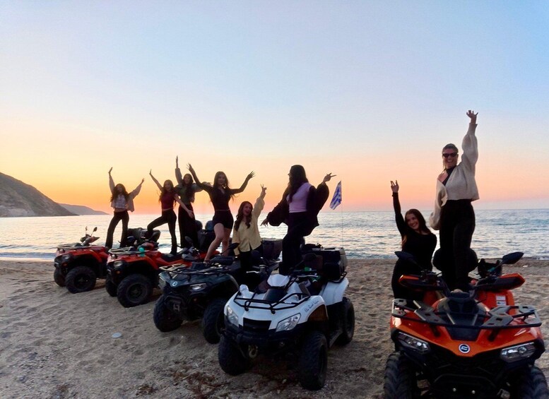 A group of people on ATVs on a beach at sunset. 2