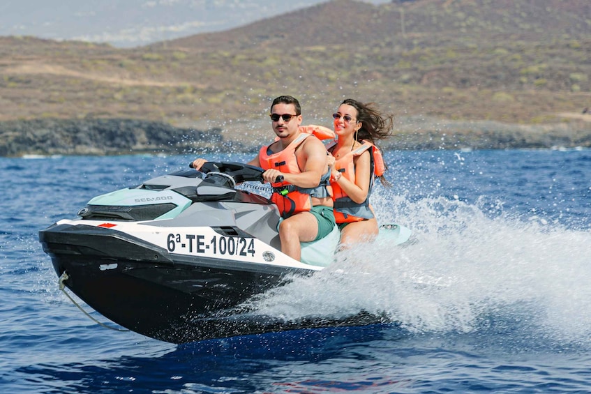 A person riding a jet ski on a body of water with a mountainous landscape in the background. 1