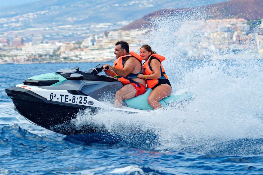 A person riding a jet ski on the water with a cityscape in the background. 4