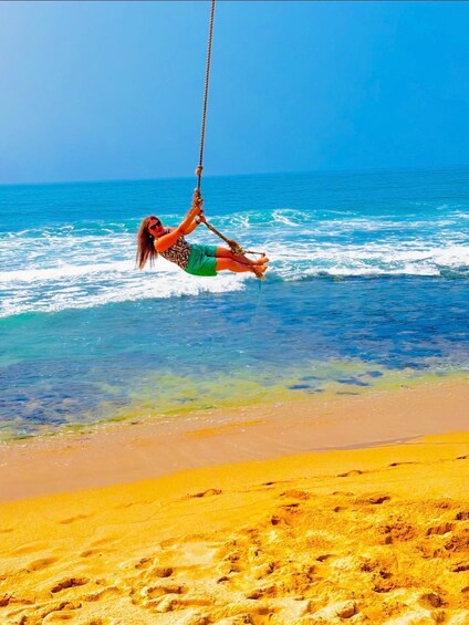 A person swinging on a rope swing over the ocean. 3