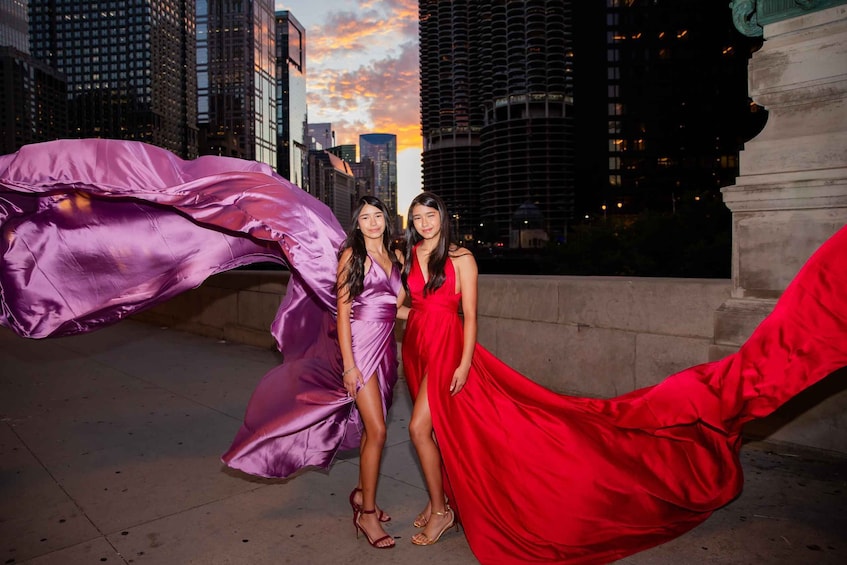 Two women in long dresses standing in an urban setting with tall buildings in the background. 4