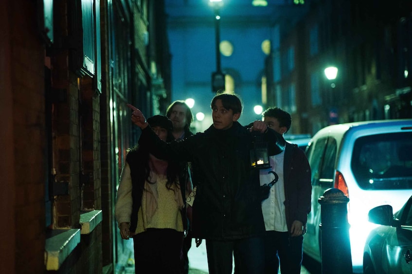 A group of people walking down a dimly lit street at night. 1
