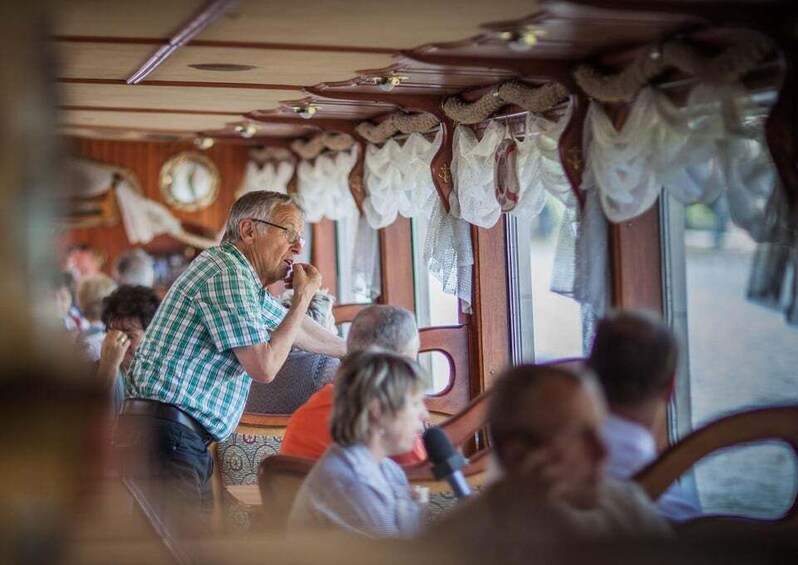 A group of people sitting inside a train car with wooden walls and curtains. 5