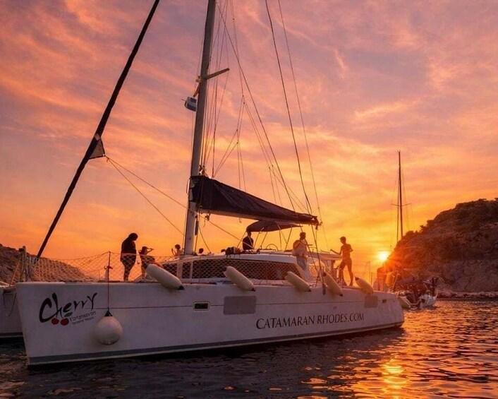 A sailboat named 'Cherry' with people on deck during sunset. 1