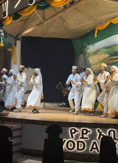 A group of people performing on a stage with a backdrop of a painted landscape. 4