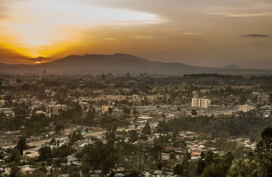 Une vue sur une ville au coucher du soleil, avec des montagnes en arrière-plan. 4