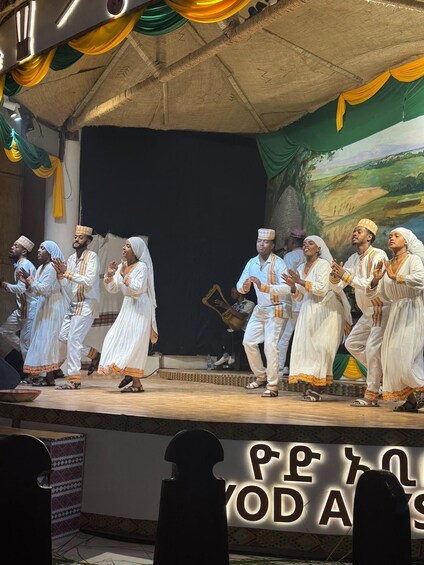 A group of people performing on a stage with a backdrop of a painted landscape. 2