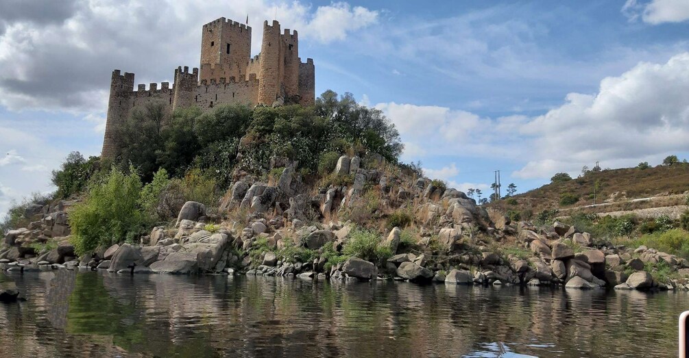 A castle on a rocky hill overlooking a calm river. 1