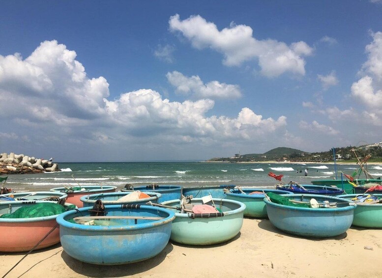 A beach with several small boats lined up on the sand, a rocky breakwater, and the ocean in the background. 3