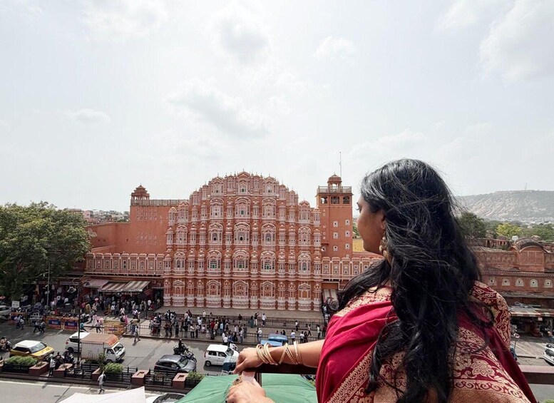 A woman in traditional attire overlooking a historic building with intricate architecture. 3