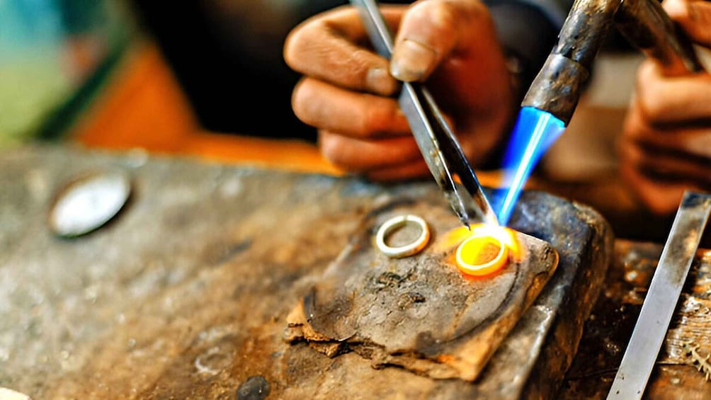 A person working with a torch on metal rings. 2