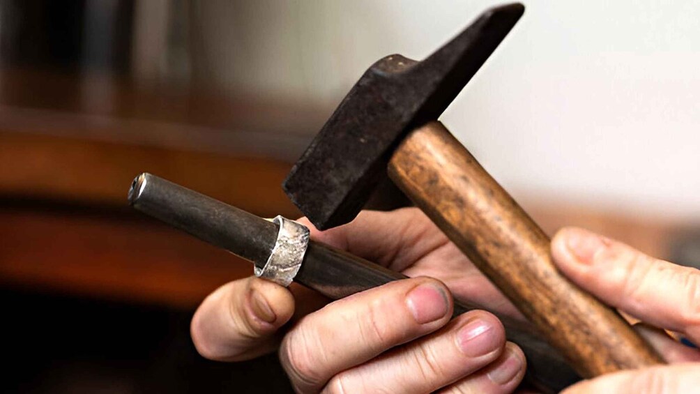 A person holding a hammer with a wooden handle and a metal head. 4