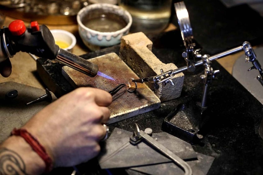 A person using a torch to heat a metal object on a workbench. 5