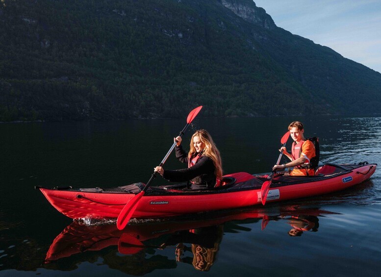 Two people kayaking on a calm lake with a mountainous backdrop. 2