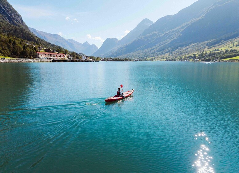 A person kayaking on a calm lake surrounded by mountains. 1