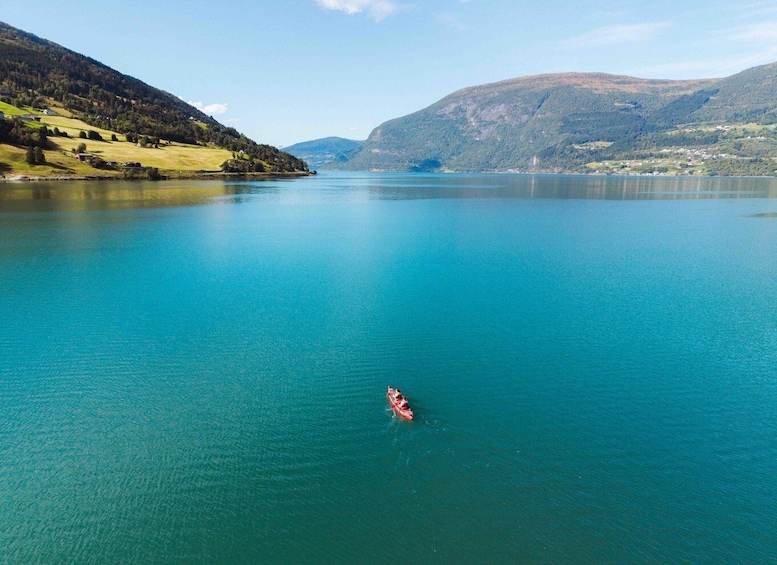 A kayaker on a calm lake surrounded by green hills and mountains. 4
