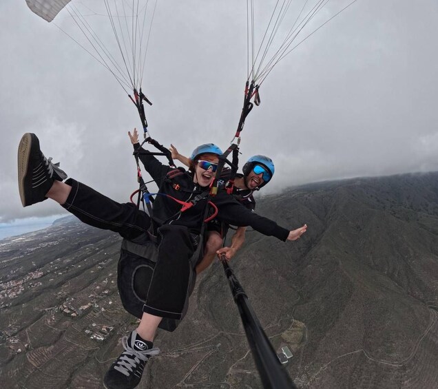 Two people paragliding with a mountainous landscape below. 4
