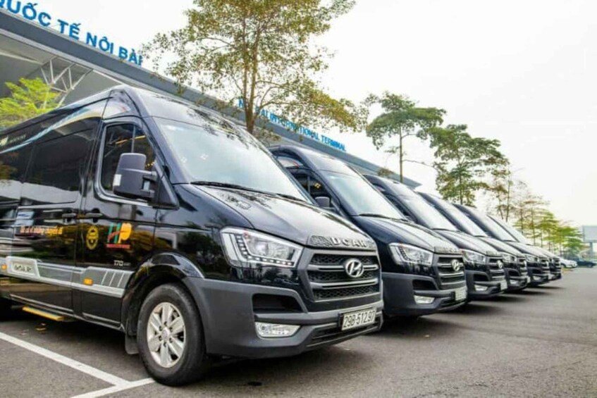 A row of black Hyundai vans parked in a lot with trees and a building in the background. 5