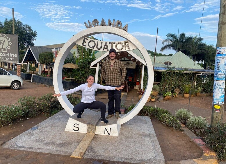 A large sign with 'UGANDA EQUATOR' and a compass-like structure with 'S' and 'N' letters. 1