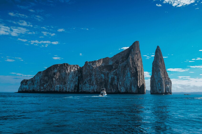 A boat navigating between two large rock formations in a blue sea under a clear sky. 3