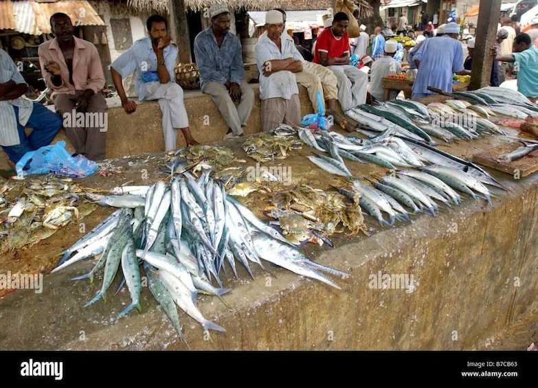 A fish market with people sitting and standing around, and fish displayed on the ground. 4