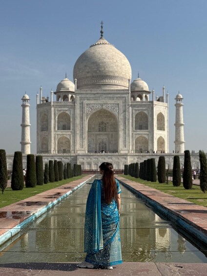 A person in a blue dress standing in front of the Taj Mahal. 4