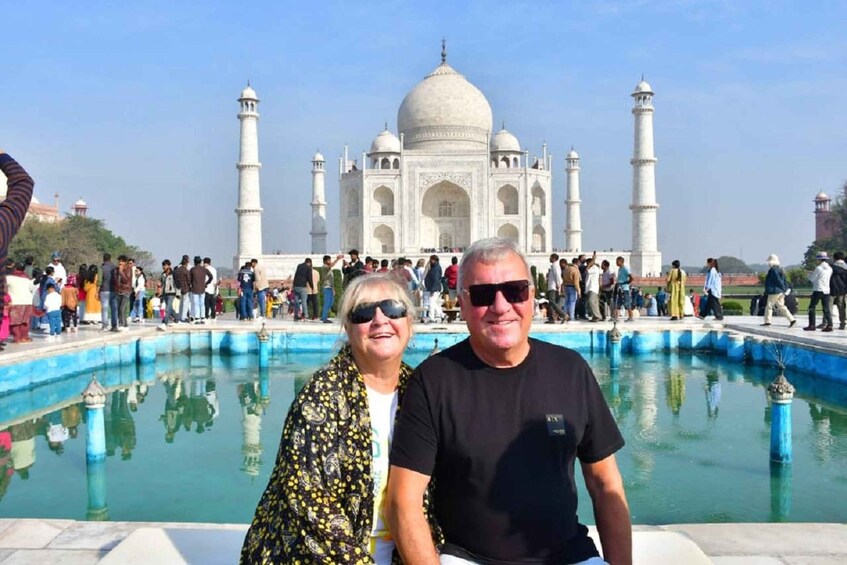 A couple sitting by a pool with the Taj Mahal in the background. 1