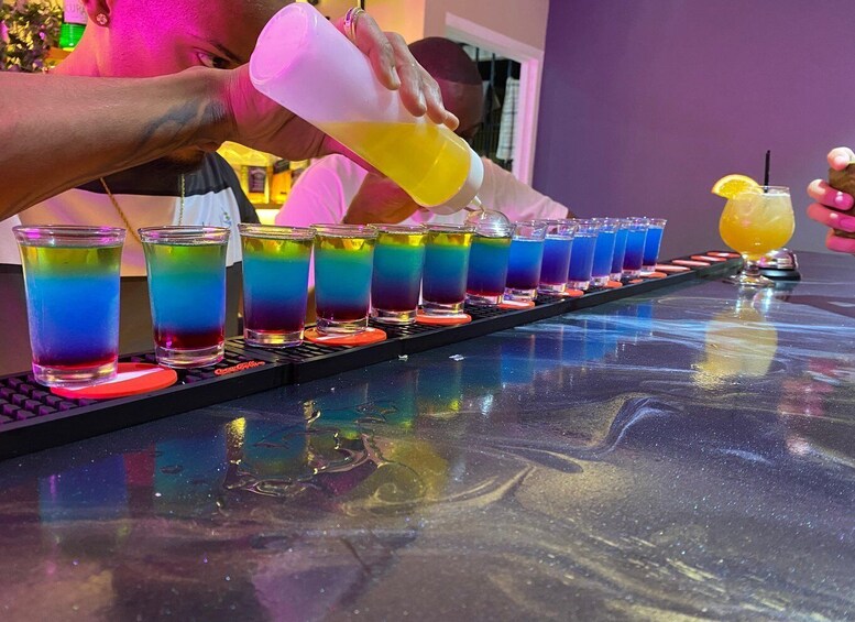 A bartender pouring a colorful drink into a glass. 1