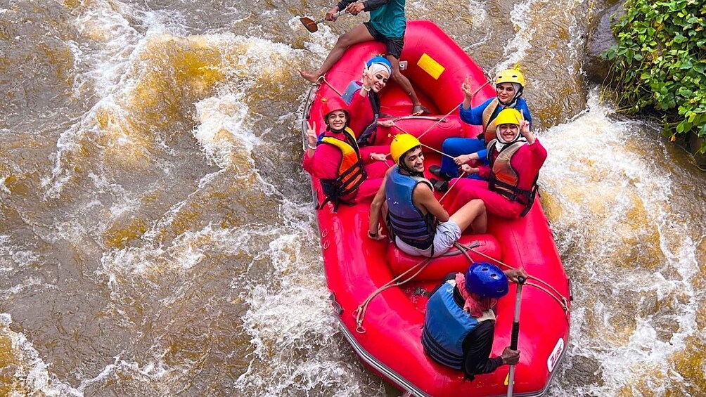 A group of people in a red inflatable raft navigating a river with white water rapids. 2