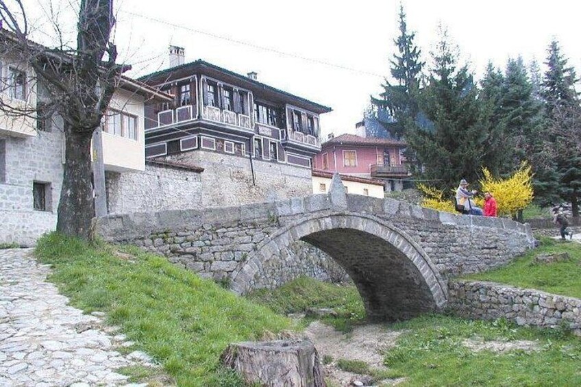 Un pont en pierre, un mur en pierre et un bâtiment doté d’un balcon. 2