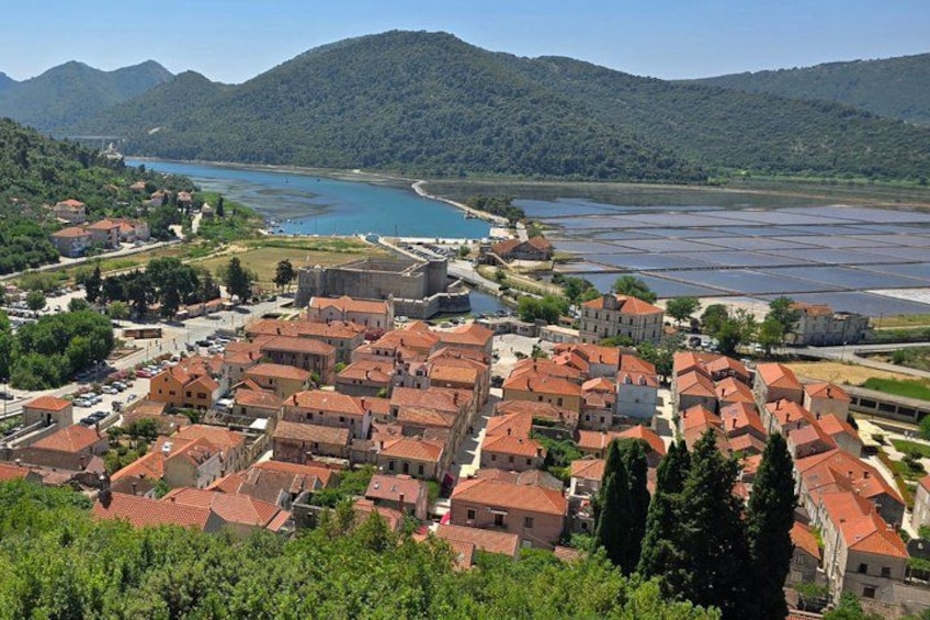 Un pueblo costero con edificios de techo rojo, un río y montañas al fondo. 1