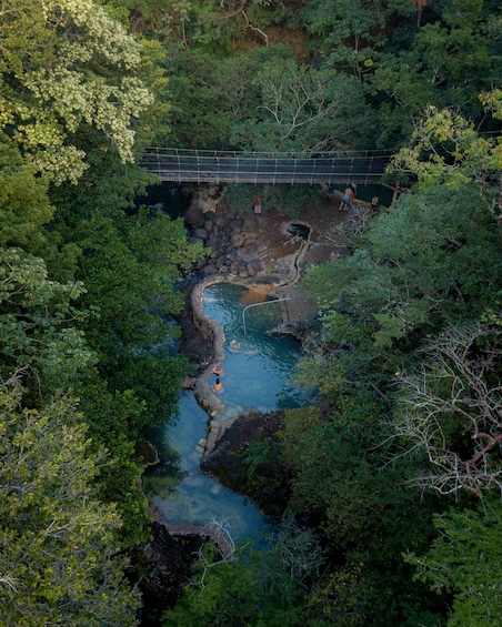 A suspension bridge over a rocky stream surrounded by dense forest. 2