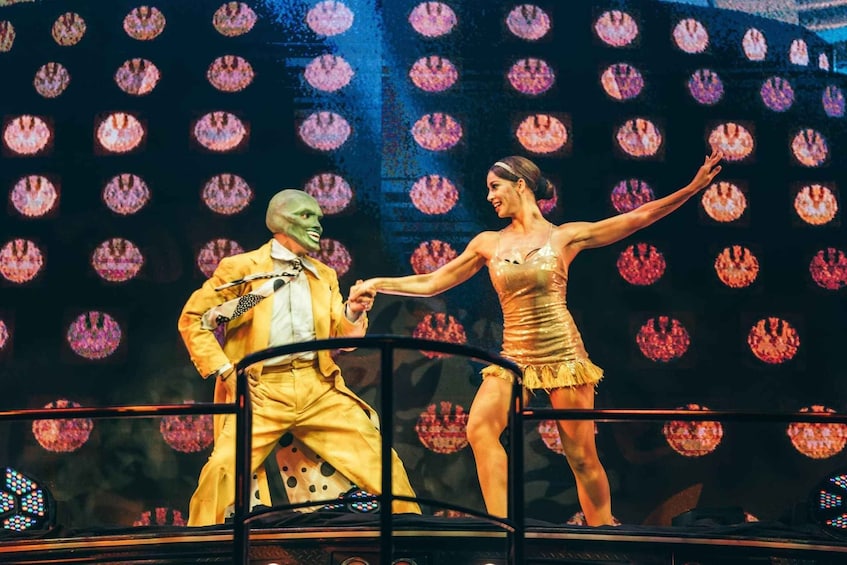 A stage with a performer in a yellow costume and a dancer in a gold dress. 4